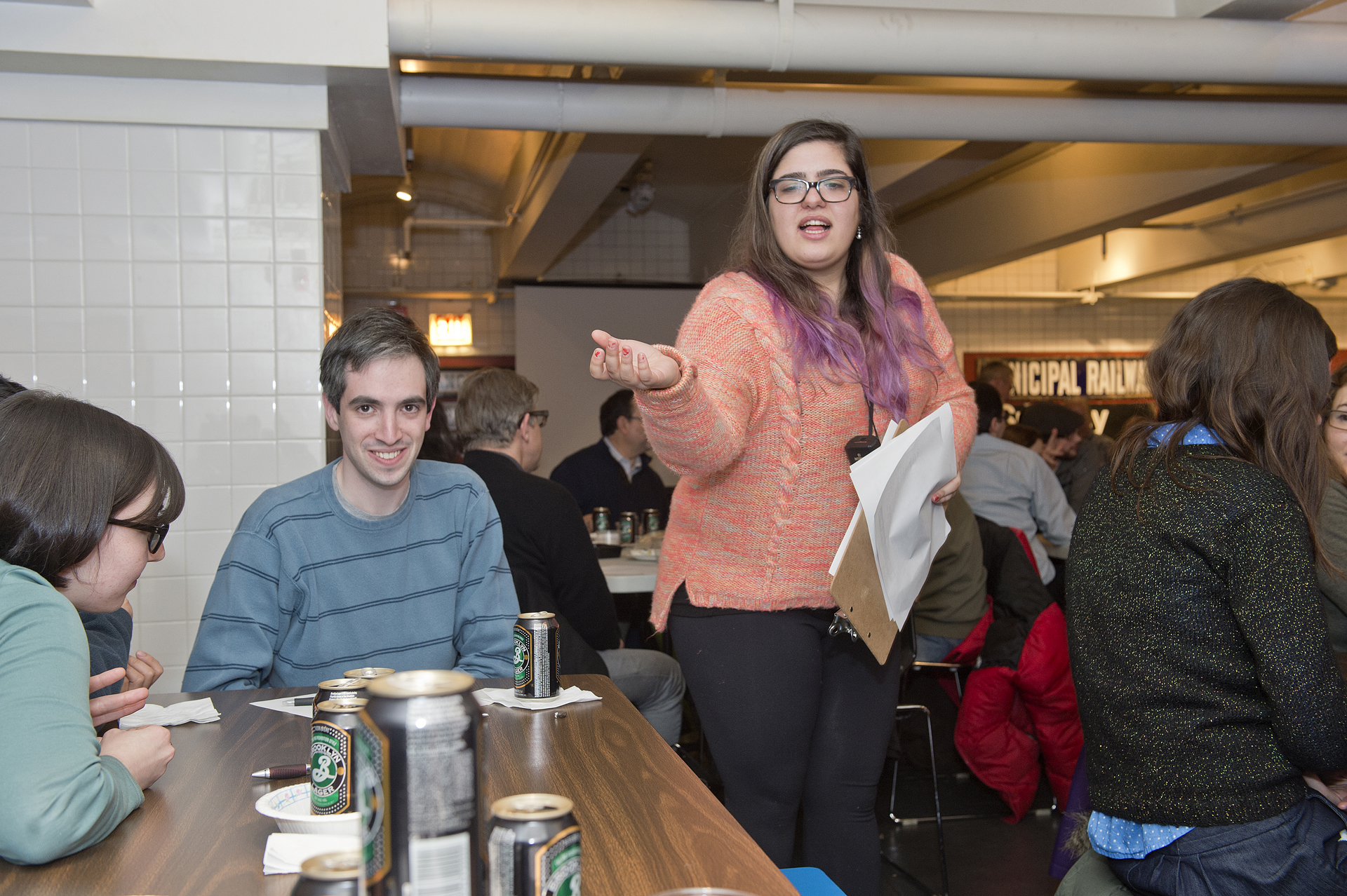 A woman leads a trivia night at a diner, fostering film culture and community with Movies Fan Club.